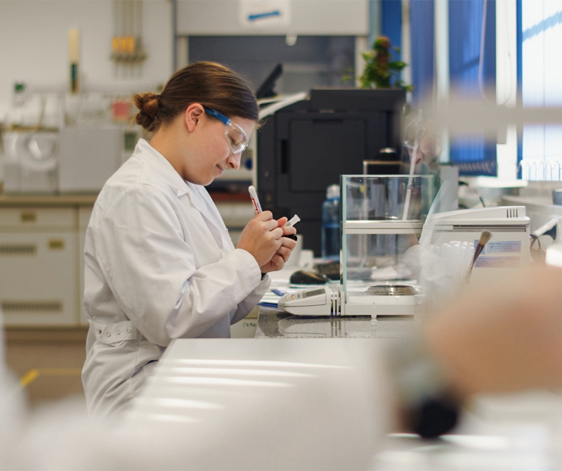 Chemielaborantin beschriftet Reagenzglas